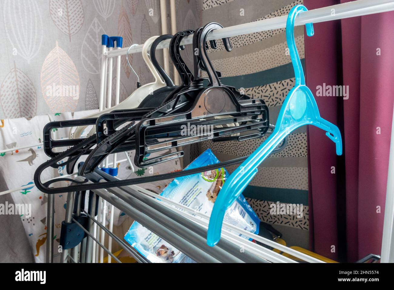 Plastic coat hangers hung from a folded up drying rack. Stock Photo