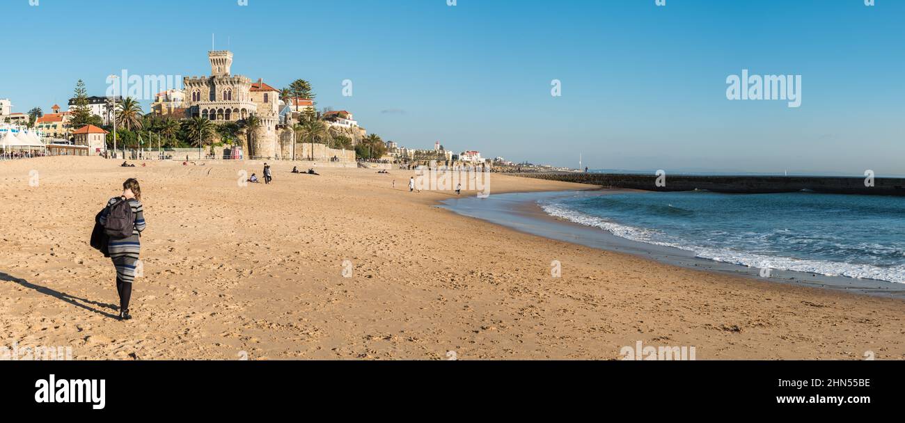 Estoril, Portugal - 12 29 2018: Extra large panoramic view of a young woman walking on the beach on a sunny winter afternoon. Stock Photo