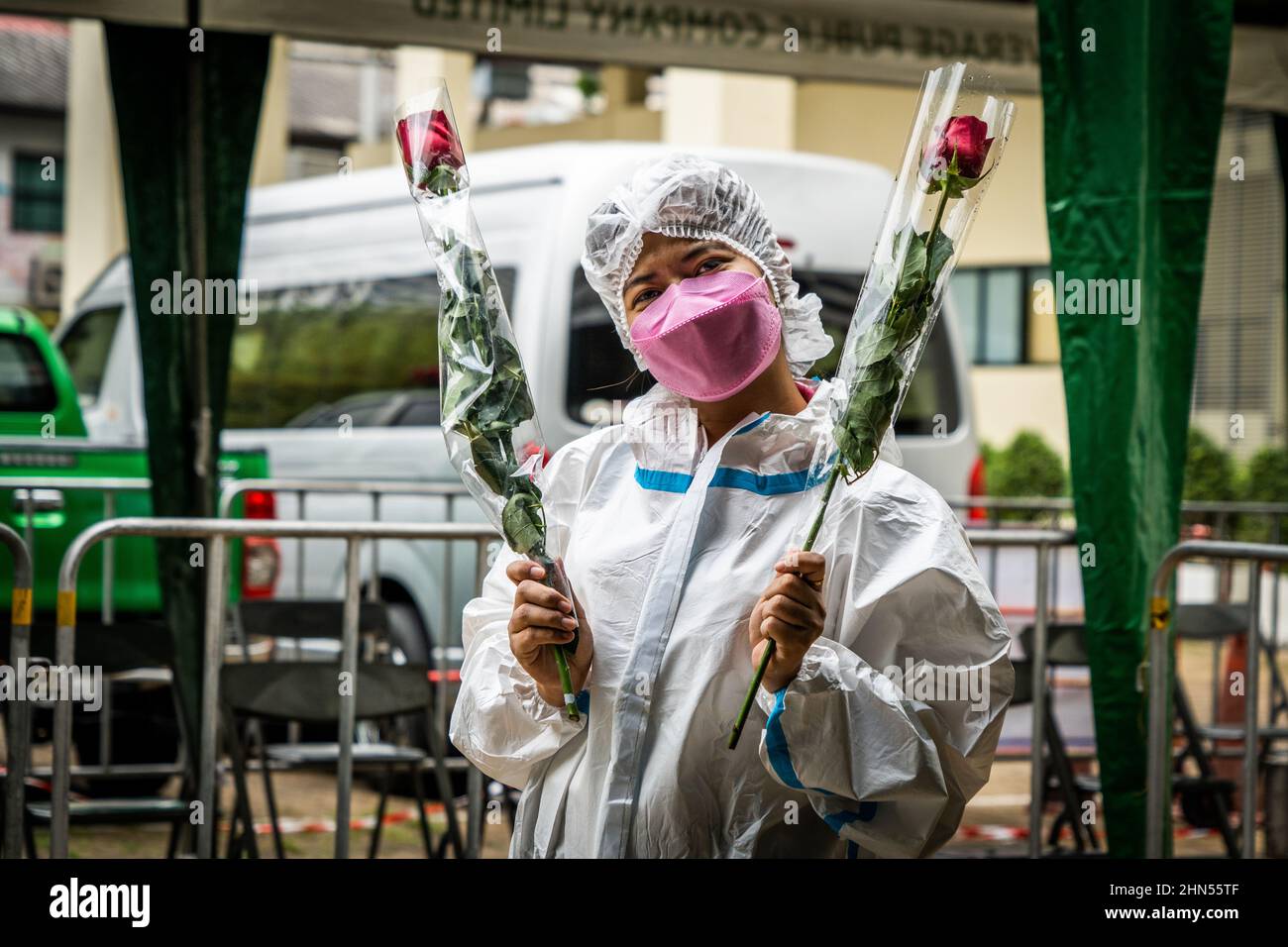 Bangkok, Thailand. 14th Feb, 2022. A medical worker dressed in full PPE poses with roses in front of a mass marriage event on Valentine's Day in Bangkok.Couples gather to legally register their marriage during the 'Lover New Normal @ Bangrak' mass marriage event on Valentine's Day in Bangkok. Although it is common for people to legalize their marriage throughout the city's 50 district offices on this day every year, Bang Rak is amongst the most popular as its name resembles 'Place of Love' in the Thai Language. Credit: SOPA Images Limited/Alamy Live News Stock Photo