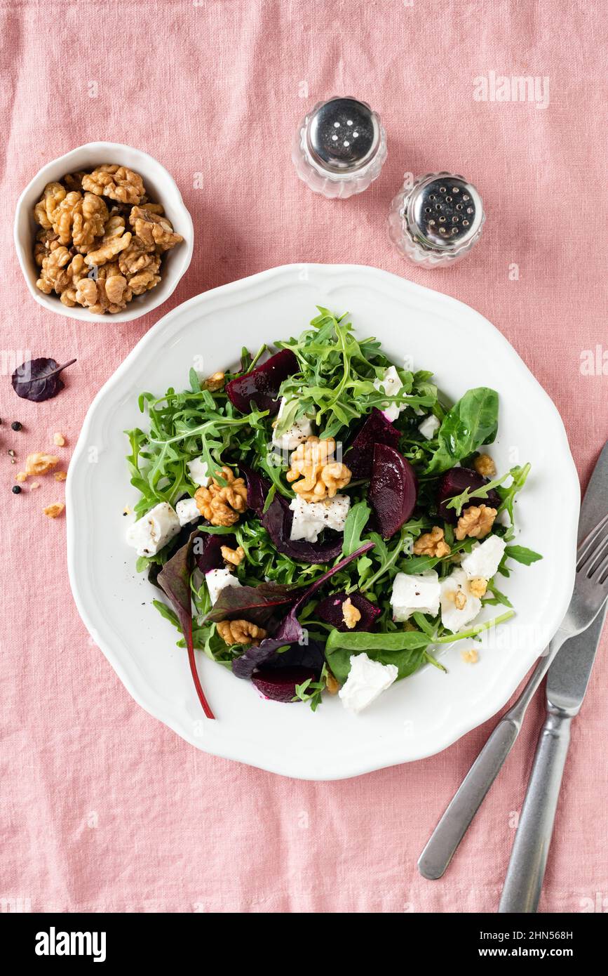 Healthy salad with arugula, walnuts, roasted beet and goats cheese on a flat plate, top view