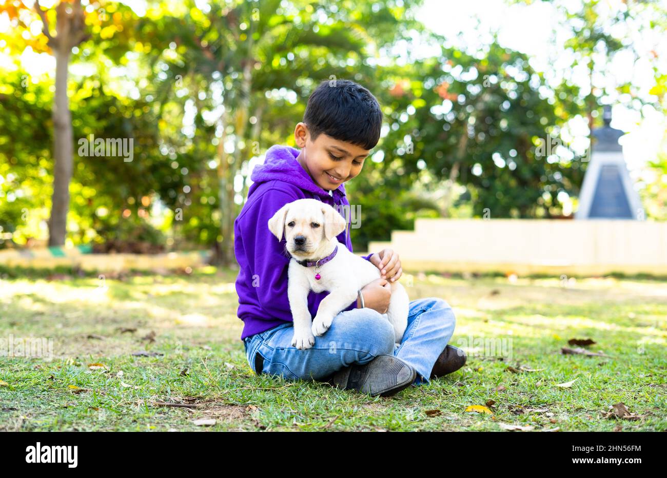 focus on dog, Young Indian Kid playing by holding puppy dog at park - concpet companion, friendship, childhood and recreation Stock Photo
