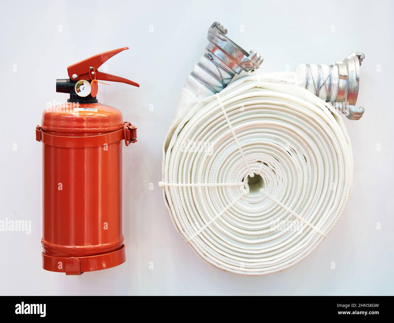 Powder fire extinguisher and fire hose on stand Stock Photo