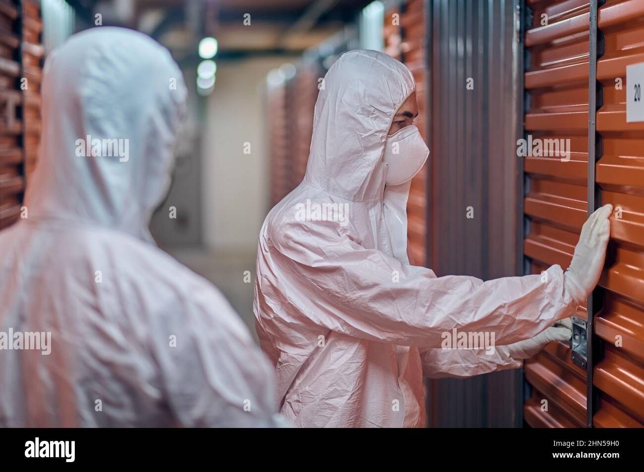 Two people in hazmat suits standing in the storehouse Stock Photo
