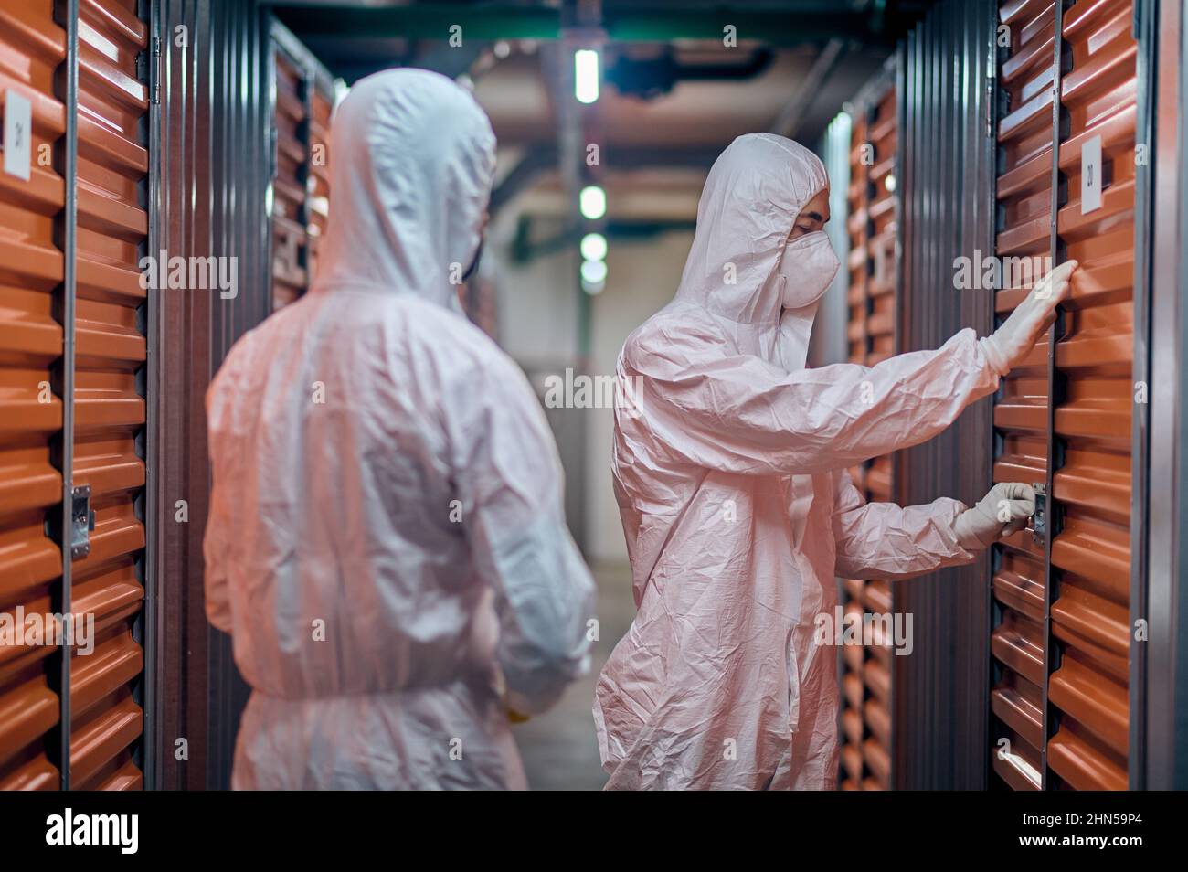 People in protective gear standing before the warehouse storage equipment Stock Photo