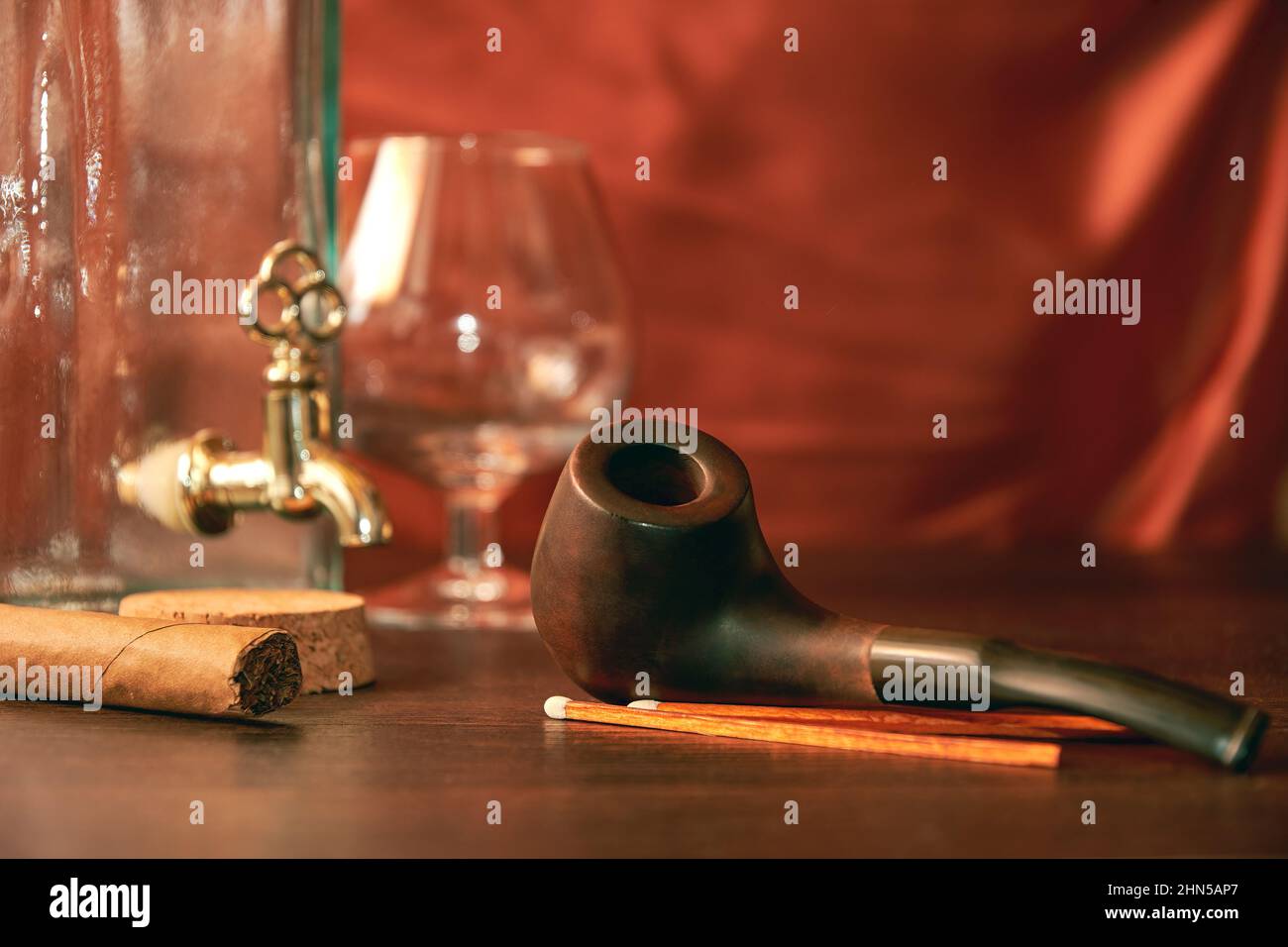 Smoking pipe with empty brandy glass and bottle and tobacco on the