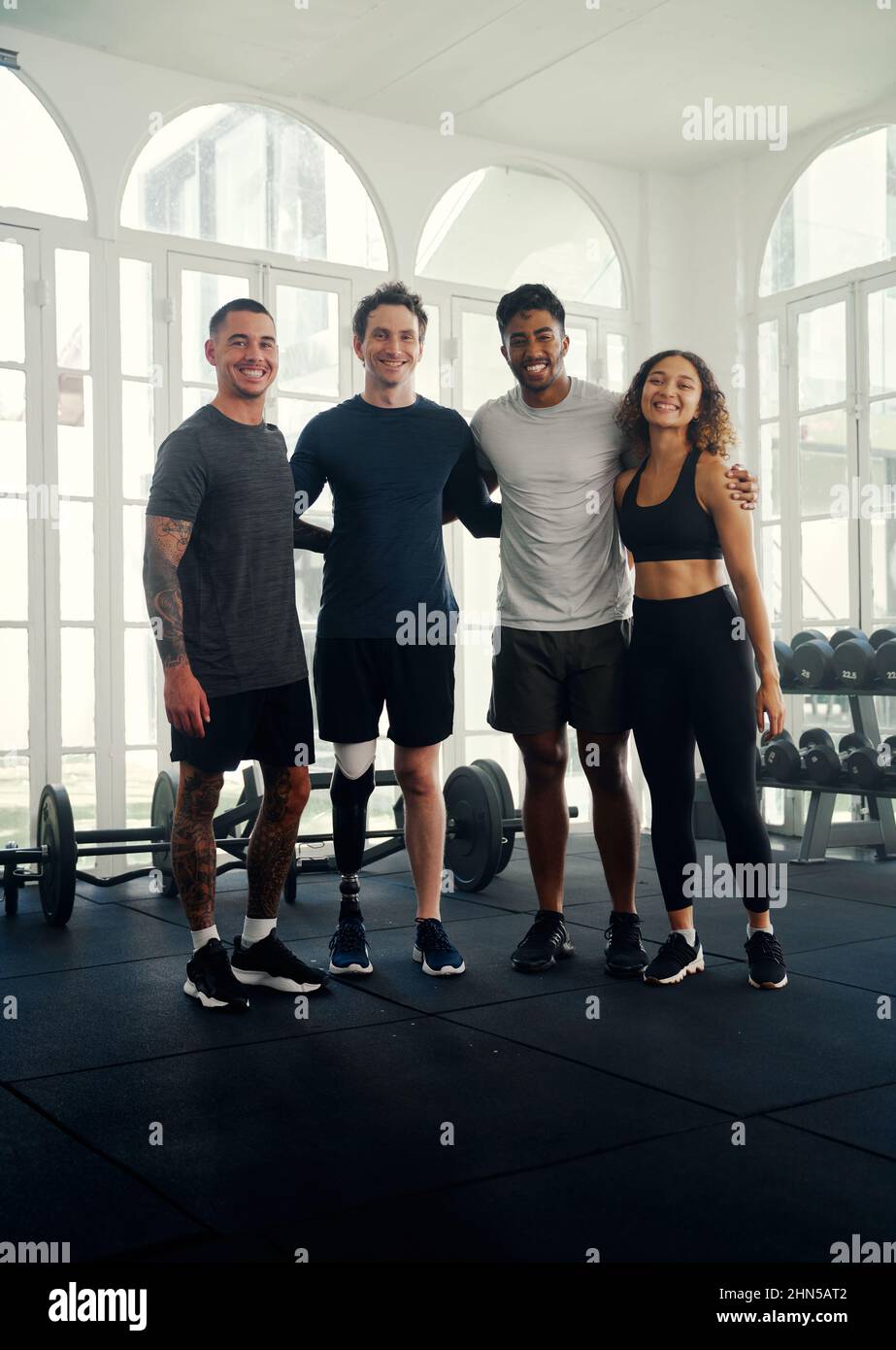 Diverse group of friends training in a modern gym . Portrait of a Multi racial friend group smiling at the camera Stock Photo