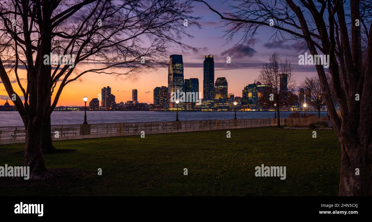 Panoramic evening view of Downtown Jersey City skyscrapers across the Hudson River. Riverfront from Battery Park (Lower Manhattan). New York Stock Photo