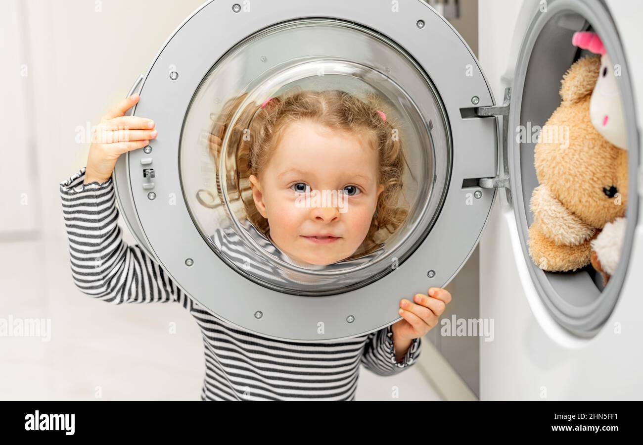 The child looks through the door of the washing machine Stock Photo Alamy