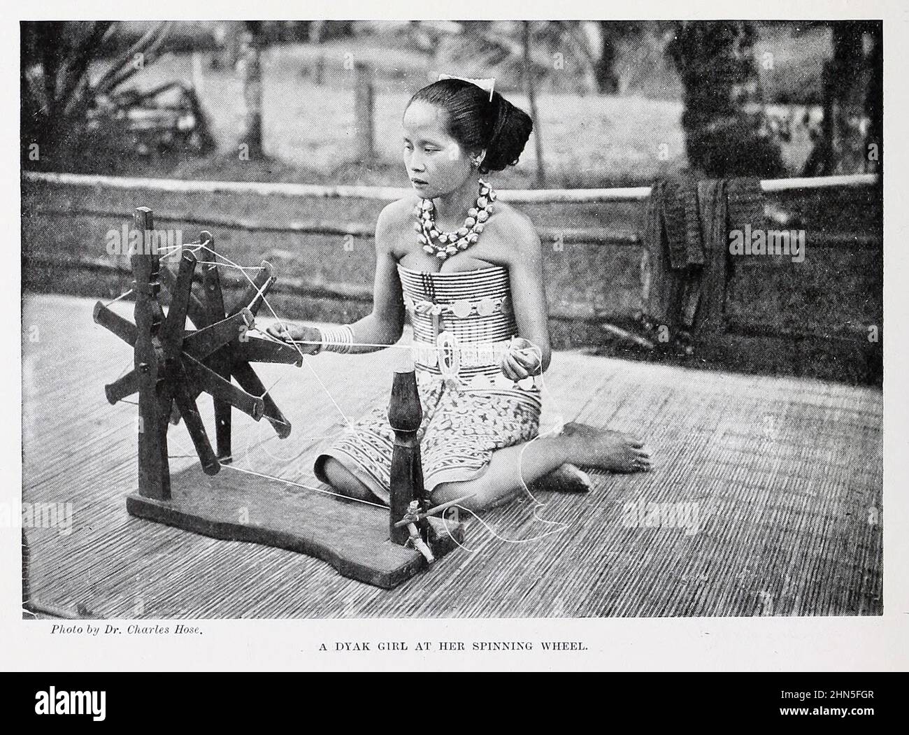 A Dyak girl at her spinning wheel. The Dayak or Dyak or Dayuh are one of the native groups of Borneo. from The living races of mankind : a popular illustrated account of the customs, habits, pursuits, feasts & ceremonies of the races of mankind throughout the world Volume 1 by Sir Harry Hamilton Johnston, Henry Neville Hutchinson, Richard Lydekker and Dr. A. H. Keane published London : Hutchinson & Co. 1902 Stock Photo