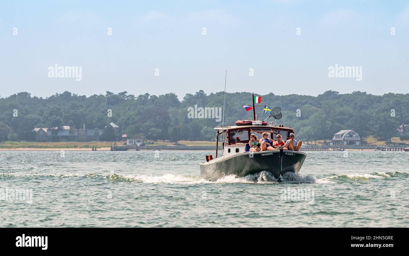 Group of people riding on the bow of an old motor yacht in Sag Harbor, NY Stock Photo