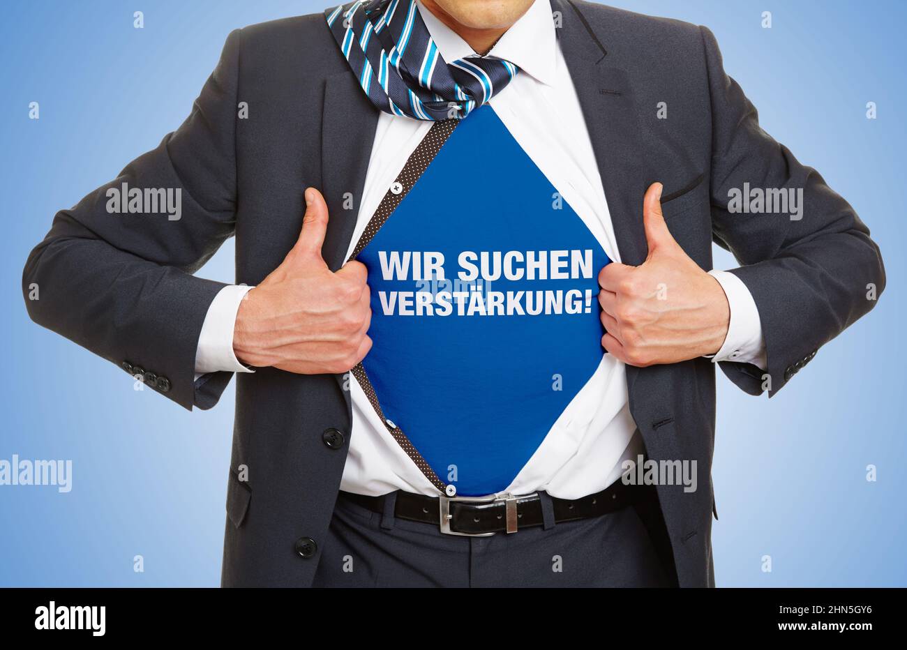 Businessman showing slogan Wir suchen Verstärkung! (German for: We are looking for reinforcements!) under shirt as human resource concept Stock Photo