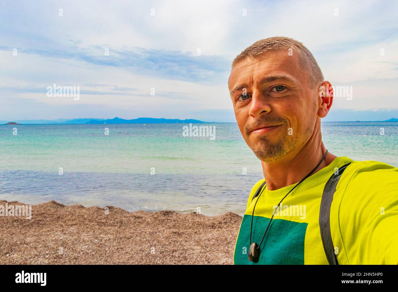 Tourist traveler model at natural green turquoise beach and water in Vouliagmeni Kavouri Beach near to Voula in Greece. Stock Photo