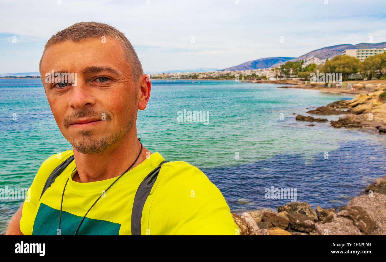 Tourist traveler model at natural green turquoise beach and water in Vouliagmeni Kavouri Beach near to Voula in Greece. Stock Photo