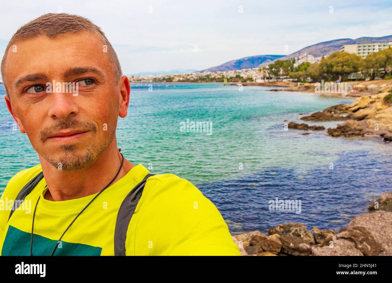 Tourist traveler model at natural green turquoise beach and water in Vouliagmeni Kavouri Beach near to Voula in Greece. Stock Photo