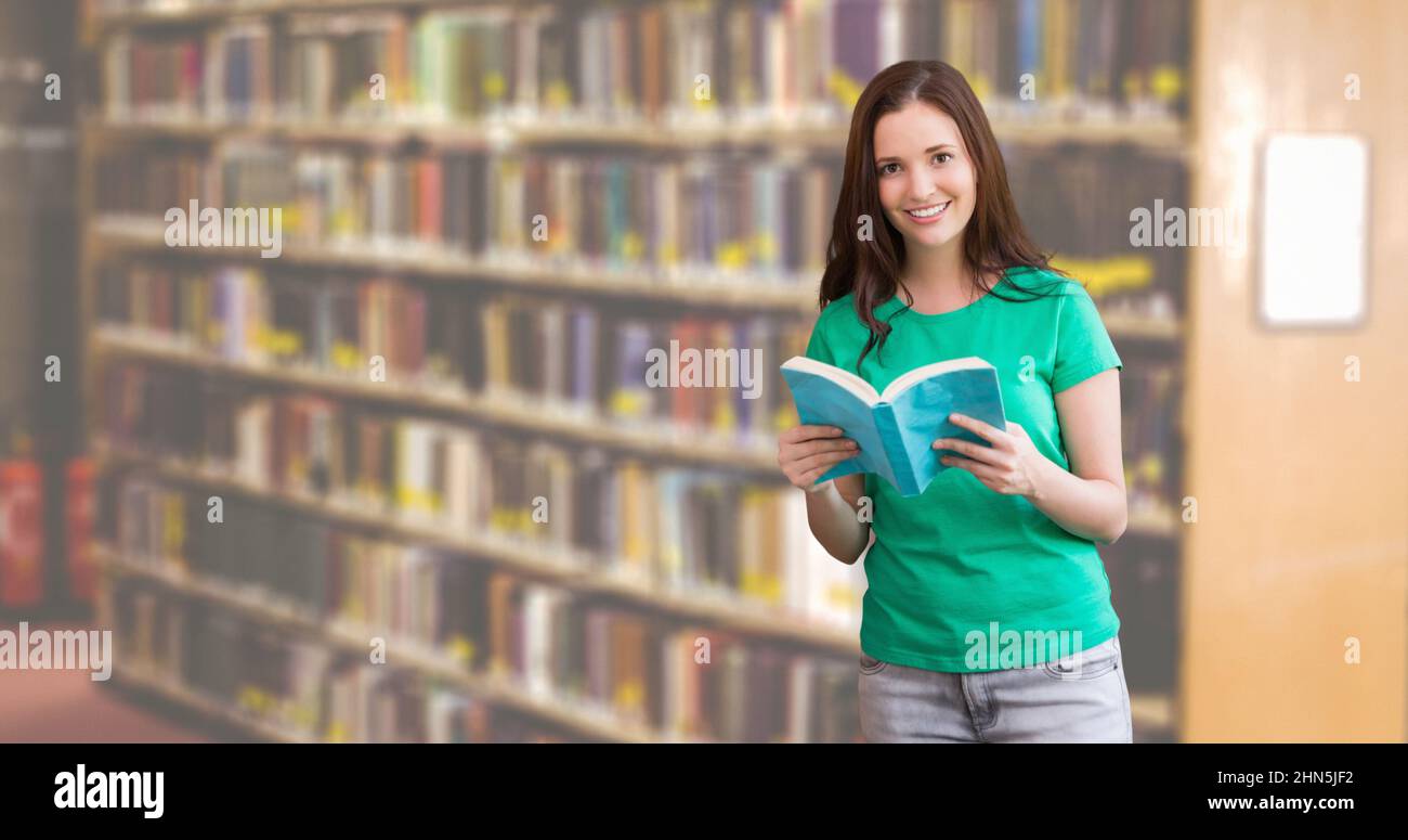 Portrait of smiling caucasian teenage girl holding book while standing ...