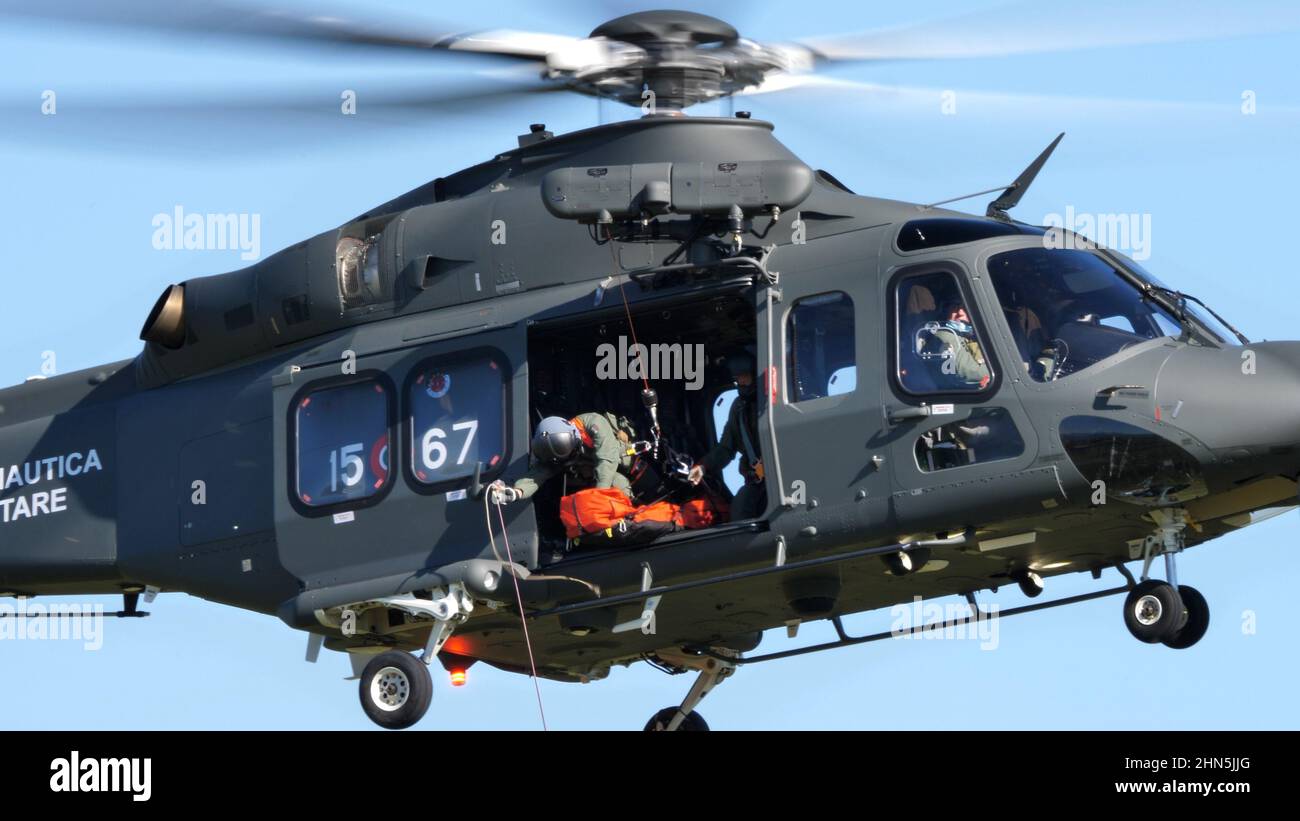 Thiene Italy, OCTOBER, 16, 2021 Rescuer prepares to alight from a military helicopter in flight with a stretcher to save a human life. AgustaWestland Stock Photo