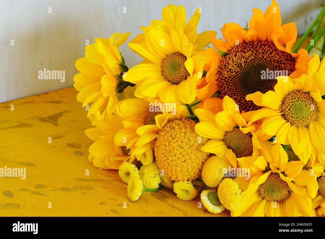 A bouquet of yellow flowers with craspedia, daisies and sunflowers Stock Photo
