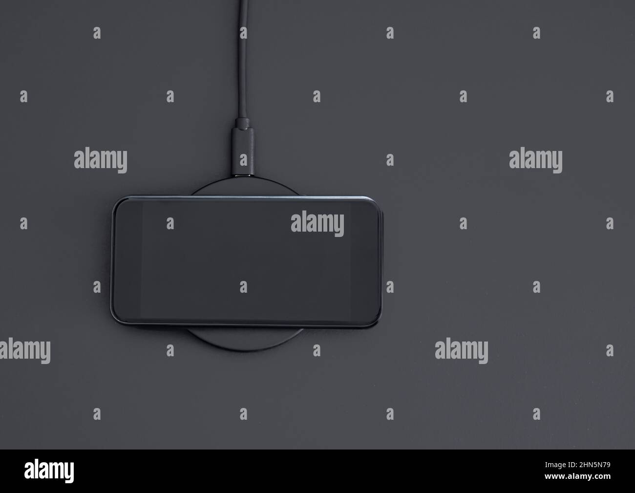 Induction wireless charging of mobile phone. High angle view of