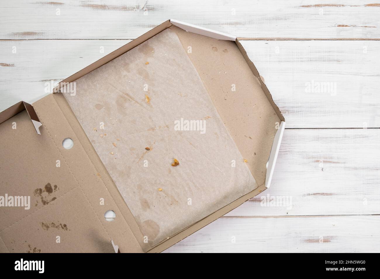 Empty open pizza box. White wooden background. Eaten pizza. Top view