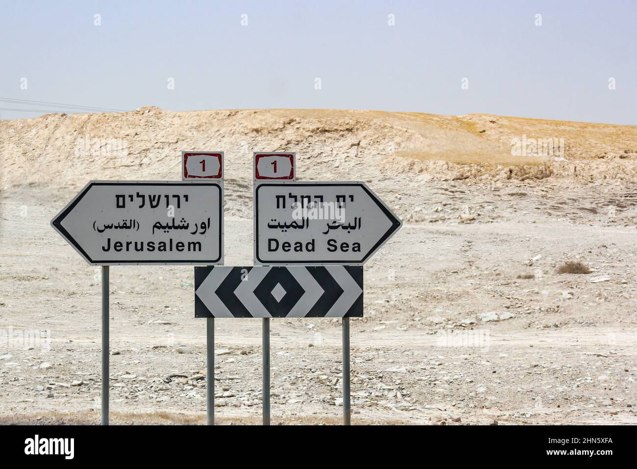 Trilingual road signs printed in Hebrew, Arabic and English along Highway 1 in the Judean Desert direct travelers to Jerusalem and the Dead Sea. Stock Photo