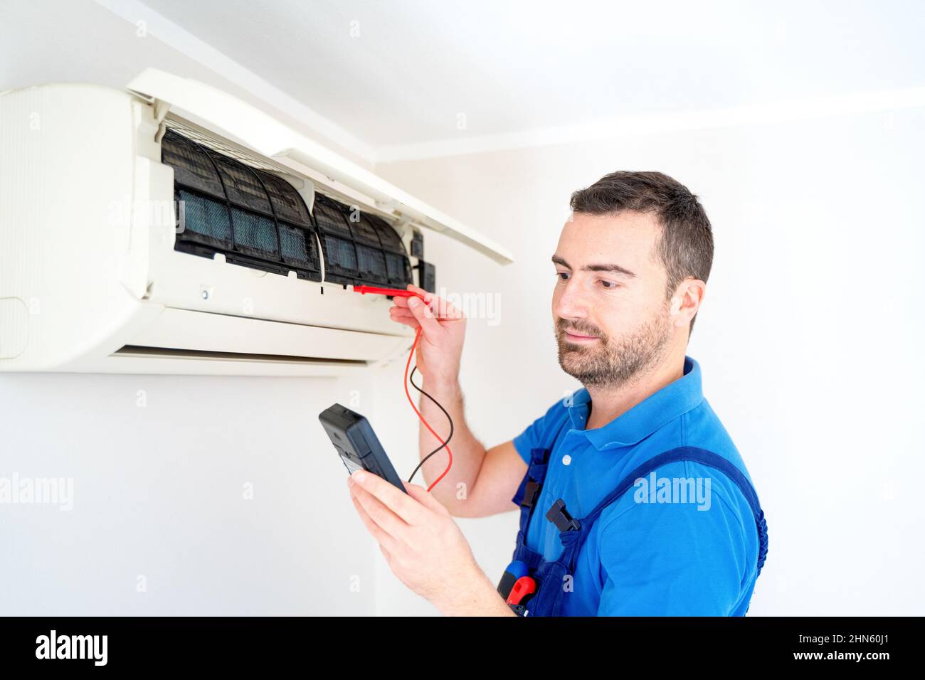 Technician installing air conditioner testing short circuit Stock Photo