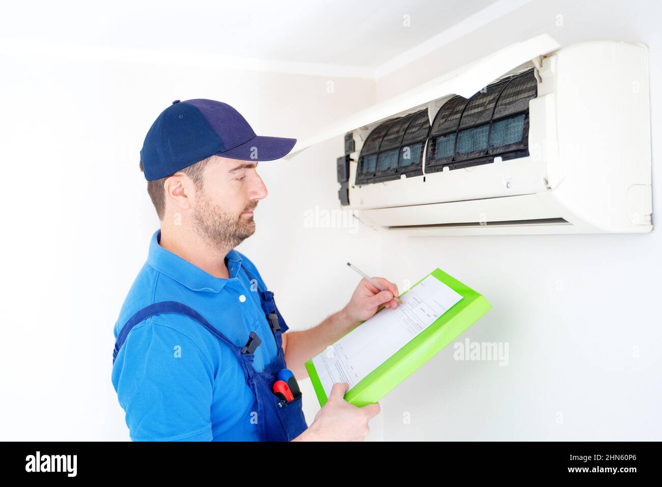 Technician with clipboard looking at air conditioner for installation