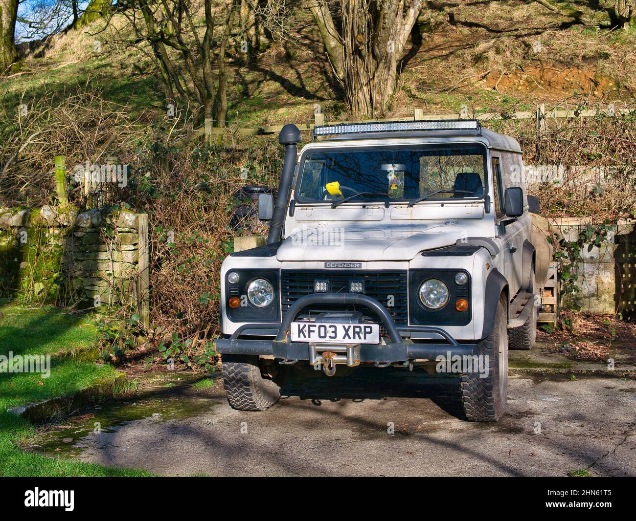A white 2003 Land Rover Defender fitted with winch, snorkel and LED lighting. Taken on a sunny day in winter. Stock Photo