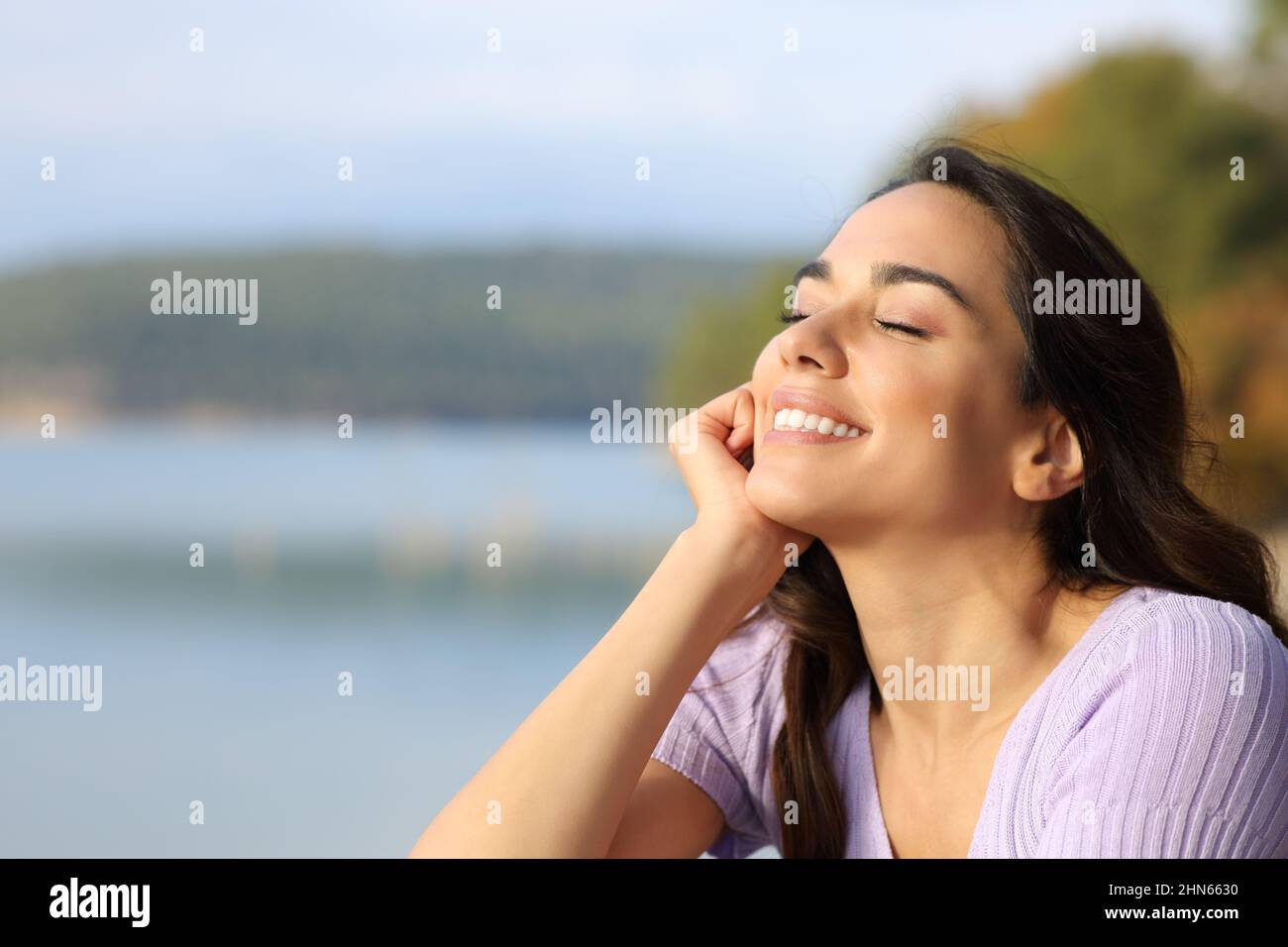 Happy woman enjoying peace sitting in a beautiful lake Stock Photo