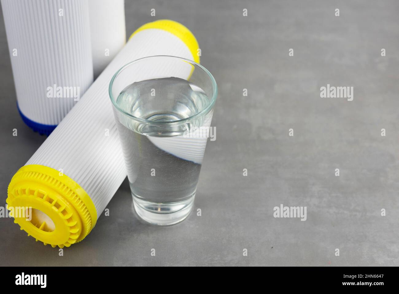 A glass of clean water next to the water purification filter. The concept of a household filtration system. Stock Photo
