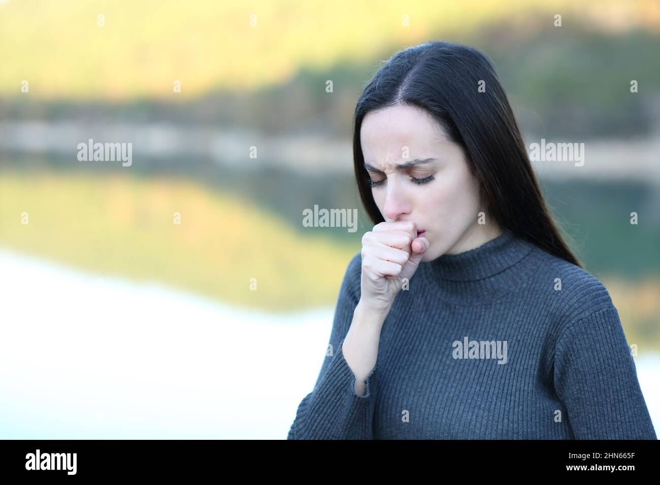 Woman coughing covering with hand in nature in winter Stock Photo