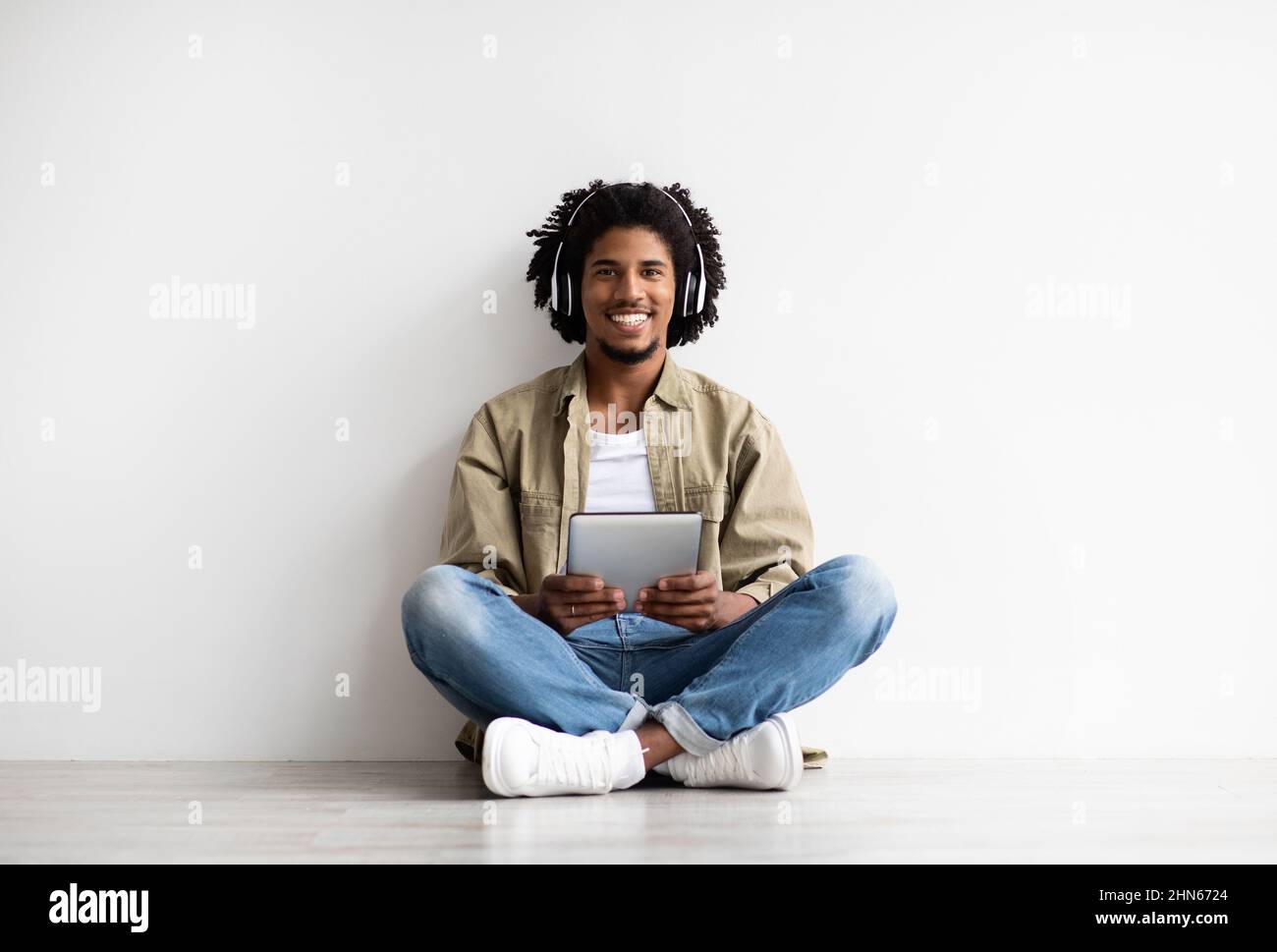 Modern Technologies. Happy Black Guy In Wireless Headphones Using Digital Tablet Stock Photo