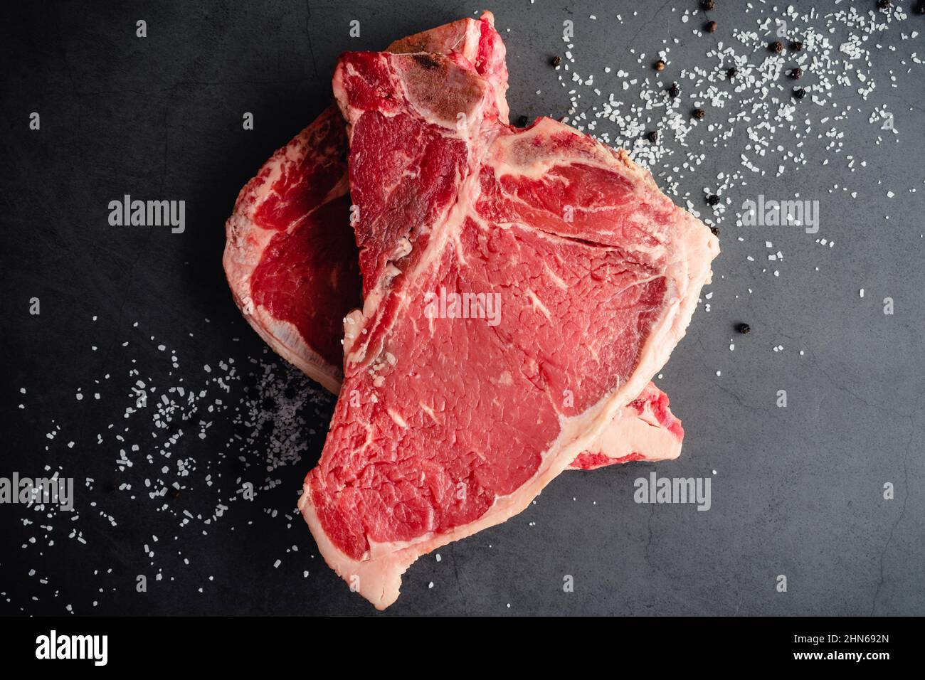 Raw TBone Steaks with Kosher Salt and Black Peppercorns Uncooked bone