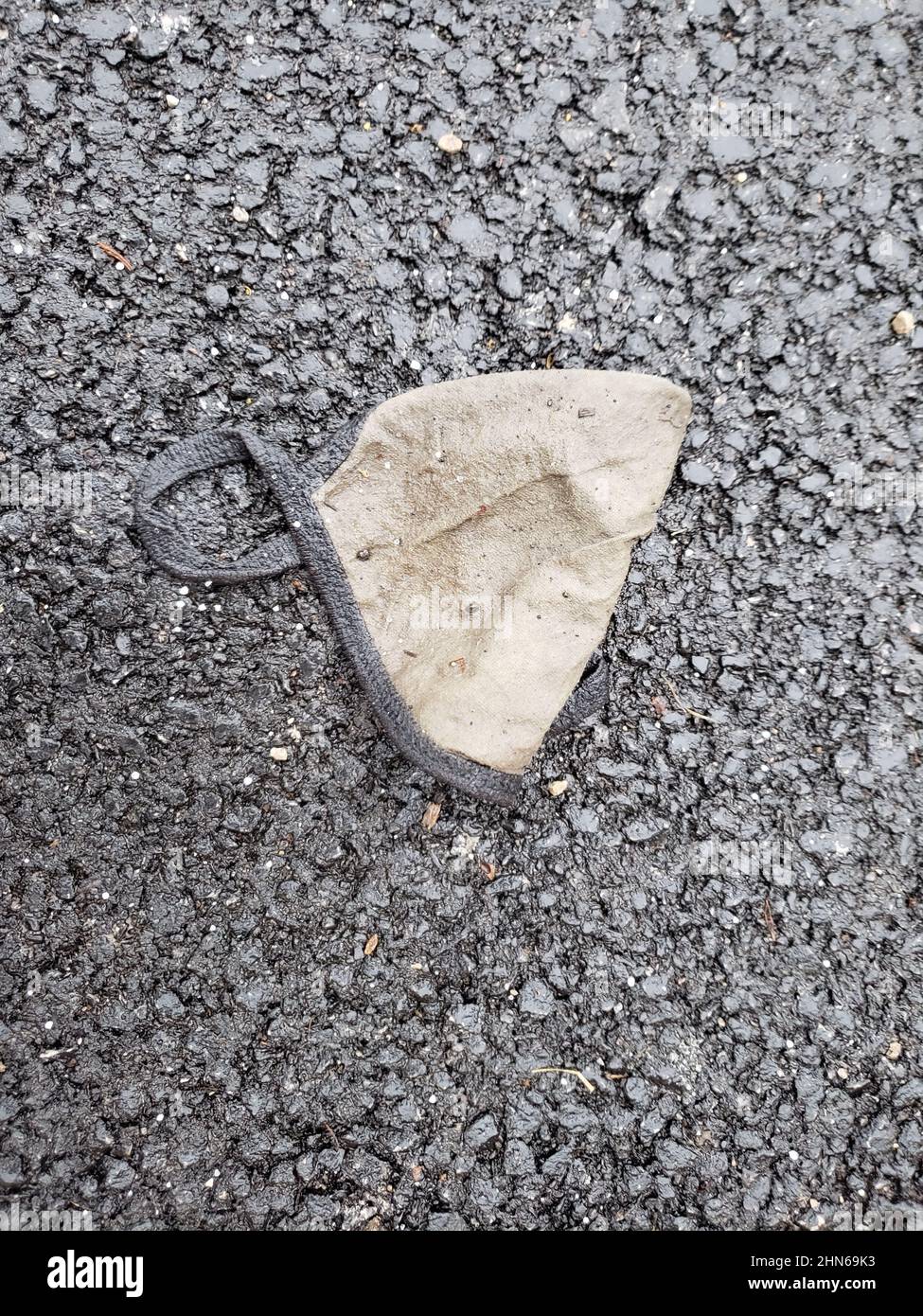 Dirty, discarded face mask on the ground Stock Photo