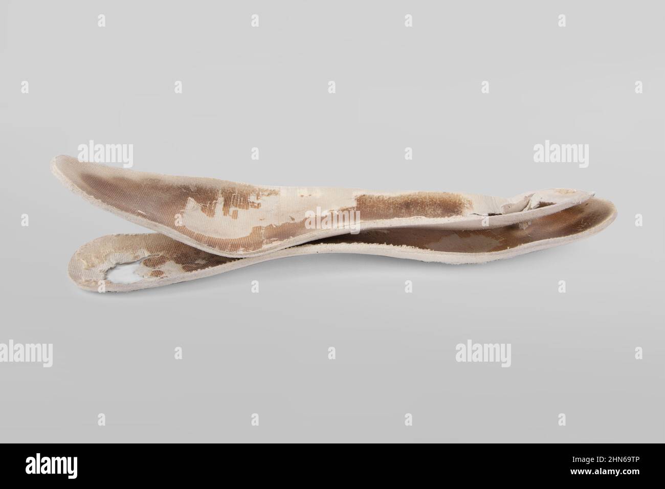 Two old, shabby orthopedic insoles isolated on gray background. Dirty