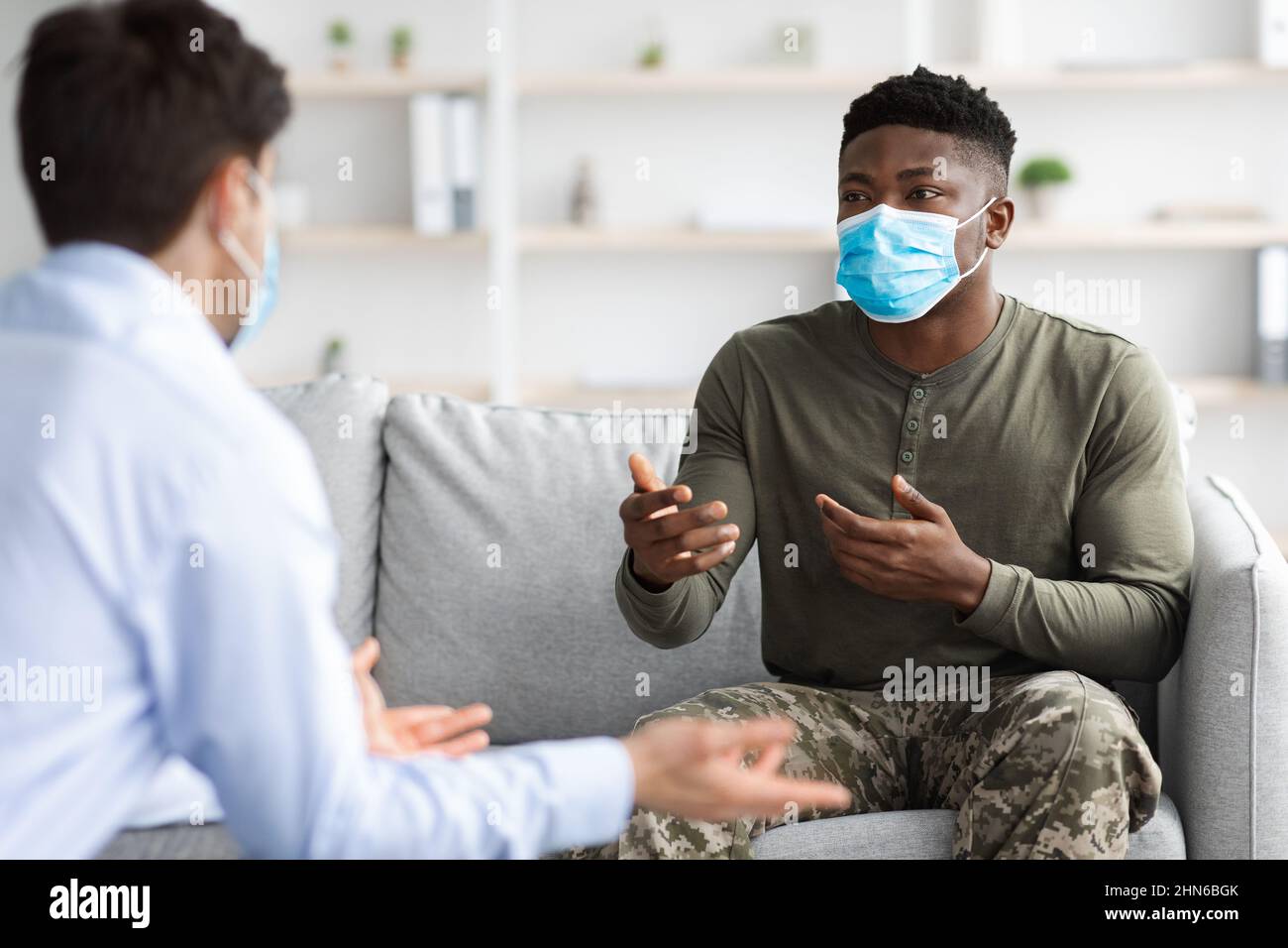 Black soldier in face mask visiting psychologist while pandemic Stock Photo