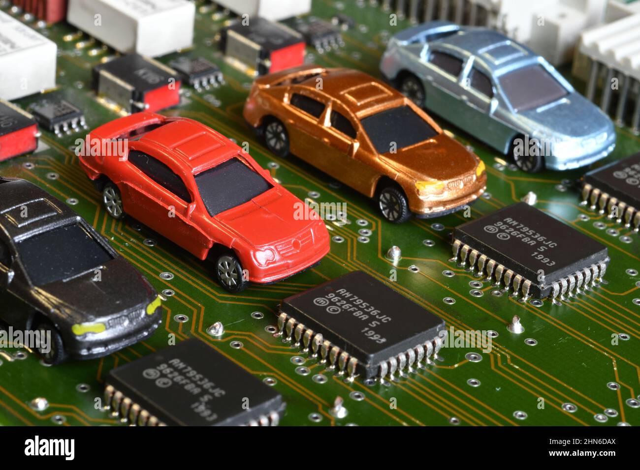 Toy cars on electronic board and microchip. The shortage of microchips