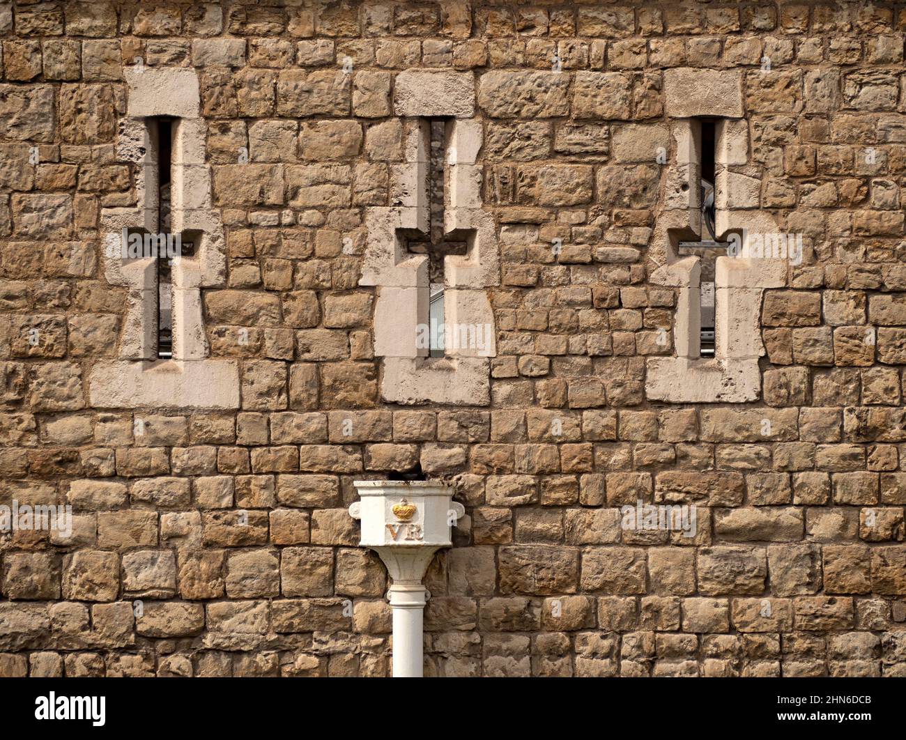 LONDON, UK - AUGUST 17, 2018:  Arrowslits in the walls of The Tower of London with Victorian drainpipe Stock Photo