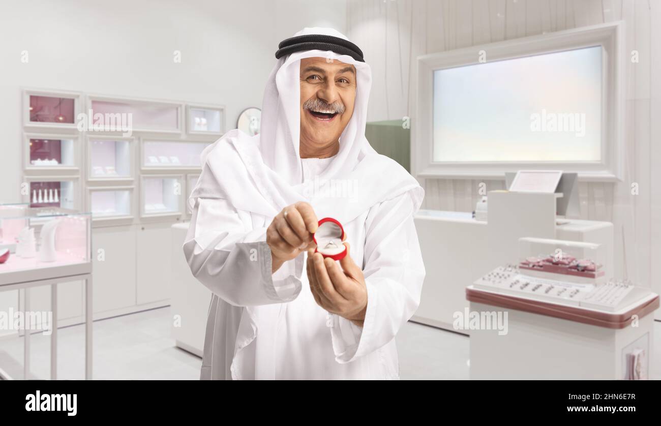 Mature arab man holding an engagement ring in a box inside a jewelry store Stock Photo