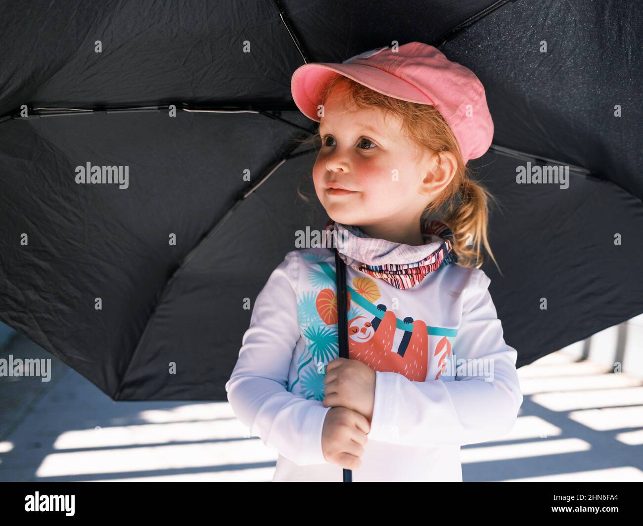 Young girl holding an umbrella for sun protection Stock Photo