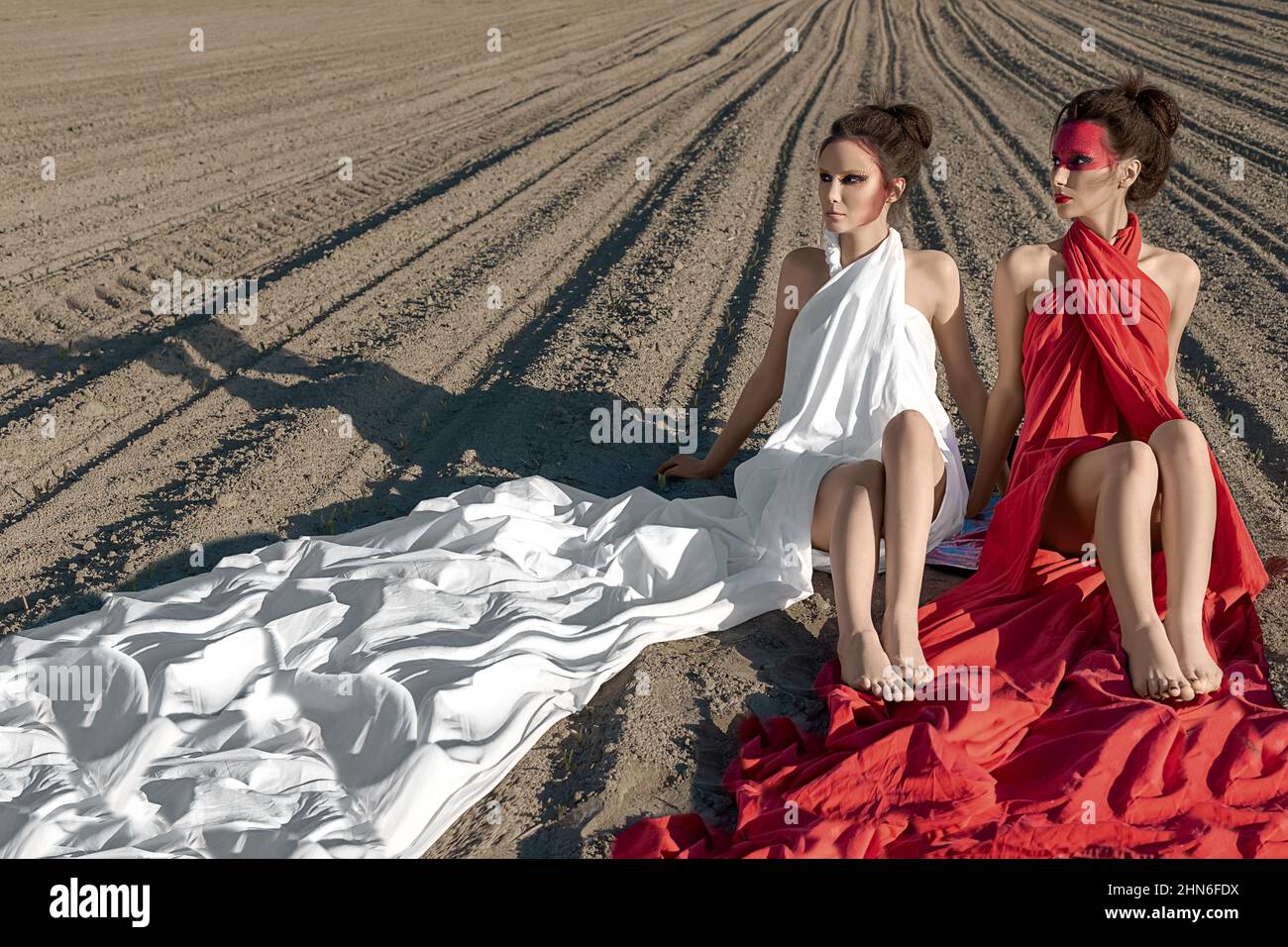 Portrait of two girls with creative body art make-up sitting on the bare ground Stock Photo