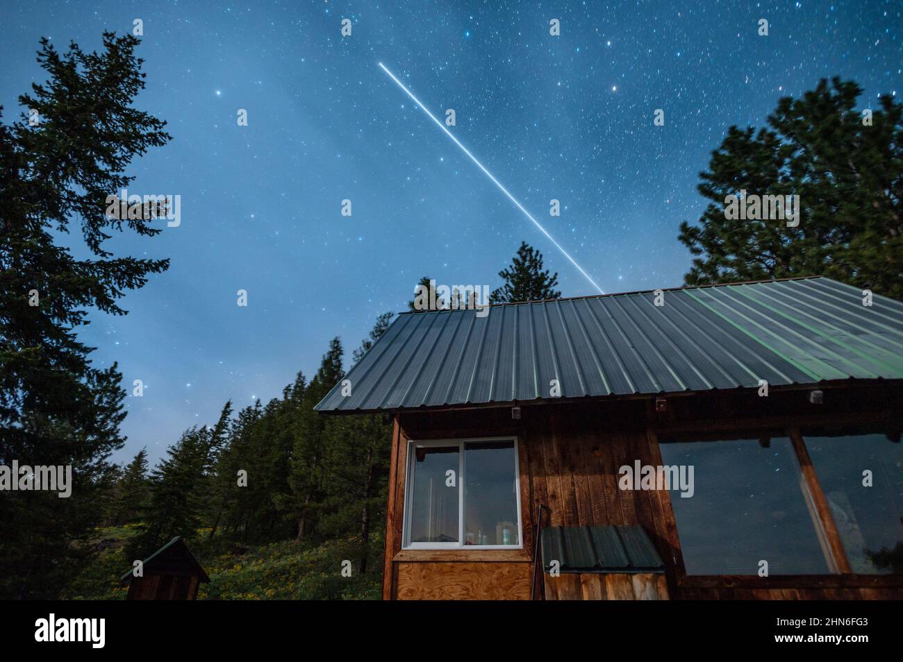 The International Space Station flying over a cabin at night Stock Photo