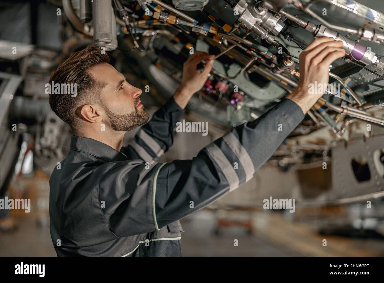Male maintenance technician repairing airplane in hangar Stock Photo