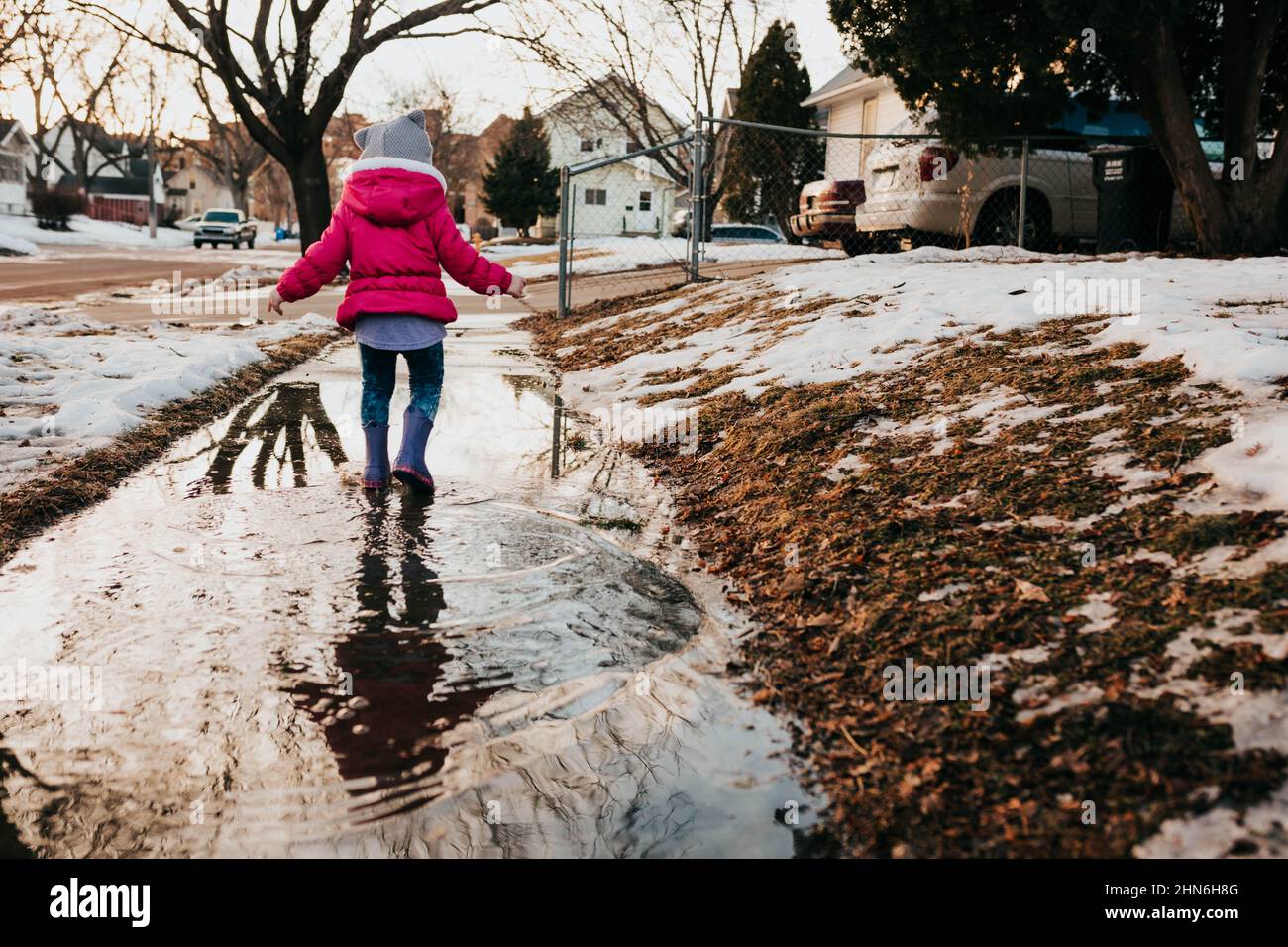 Young girl runs through sidewalk puddle in rubber boots Stock Photo - Alamy