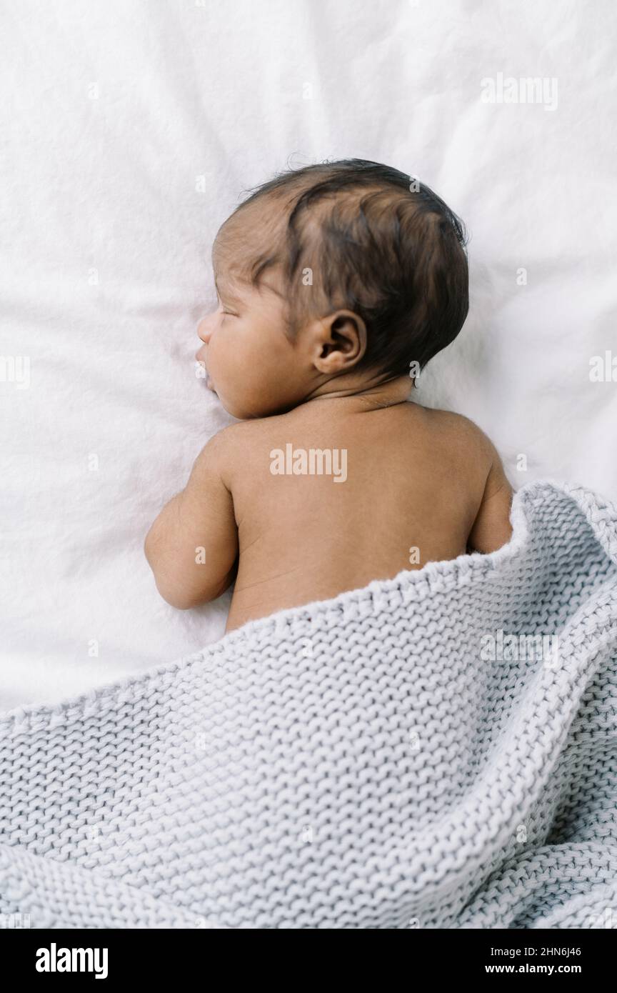 Little newborn baby boy sleeping on a bed with knit blanket Stock Photo