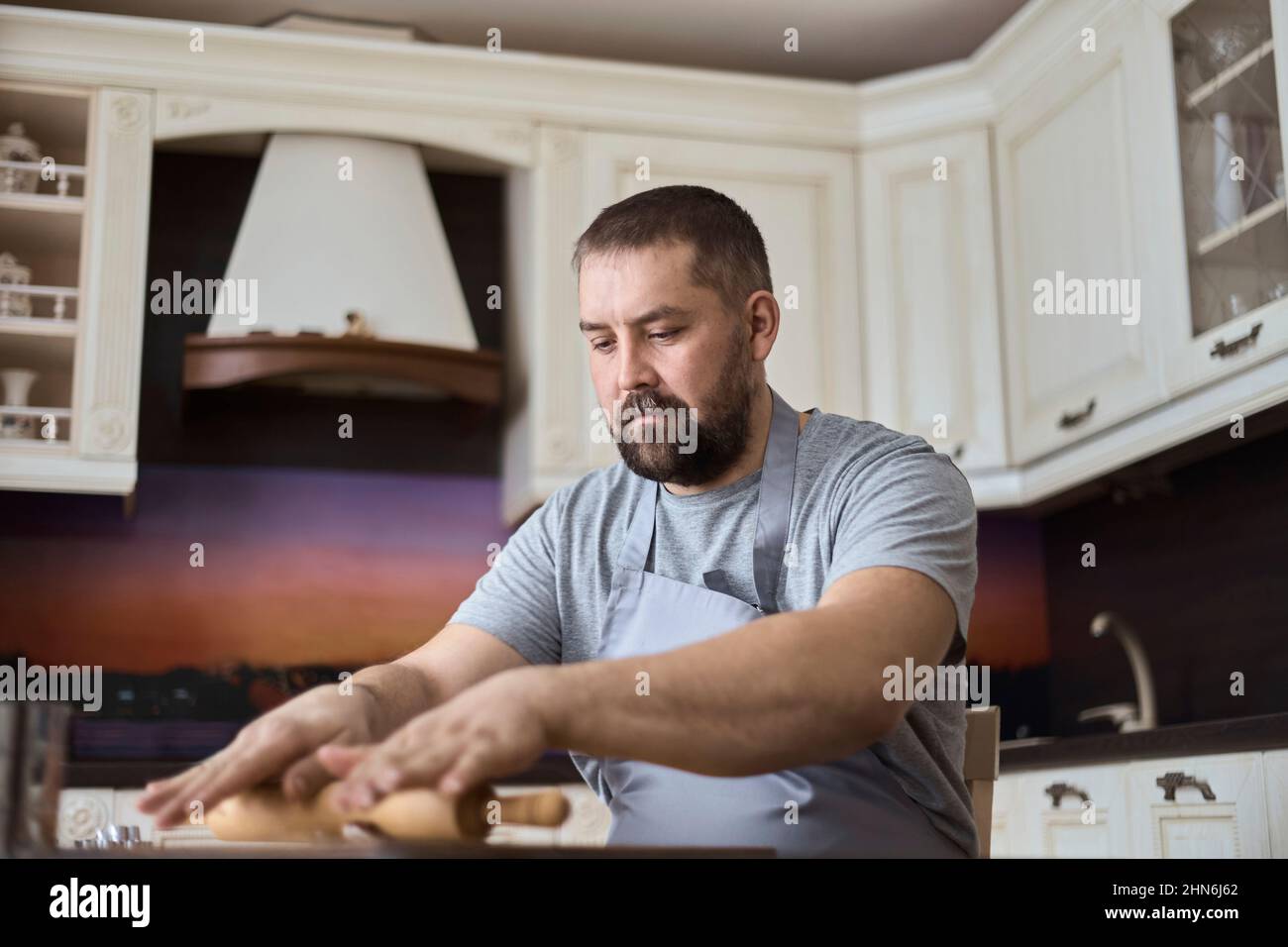 A man is rolling out dough in the kitchen Stock Photo