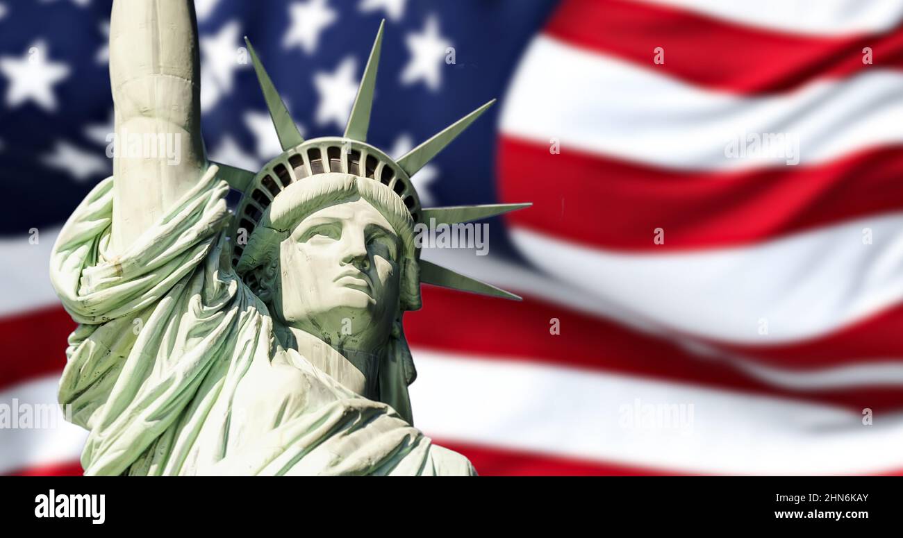 the statue of liberty with blurred american flag waving in the background. Democracy and freedom concept. Stock Photo
