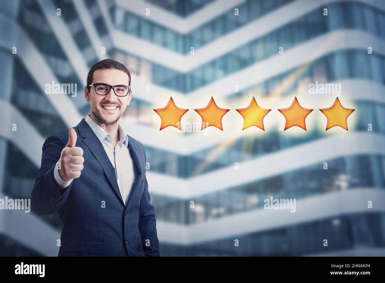 Cheerful businessman shows thumb up gesture, approvement sign, giving 5 stars rating feedback. Business person evaluating an experience, excellent cus Stock Photo