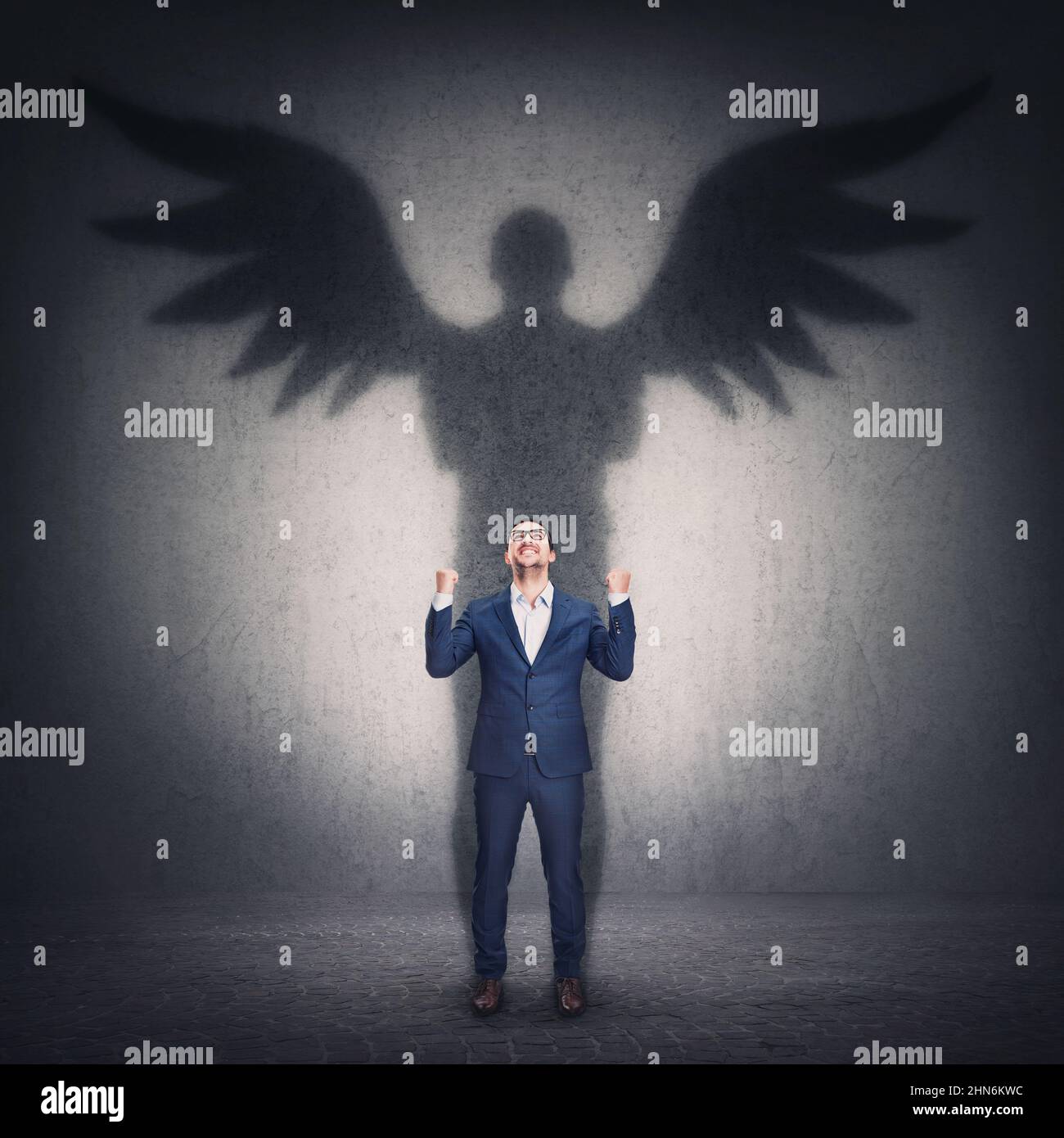 Business metaphor with a person casting a hero shadow on the wall. Powerful superhero or guardian angel with wings. Inner strength and ambition, leade Stock Photo