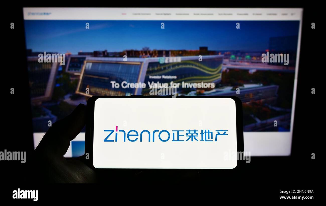 Person holding smartphone with logo of Chinese company Zhenro Properties Group Limited on screen
