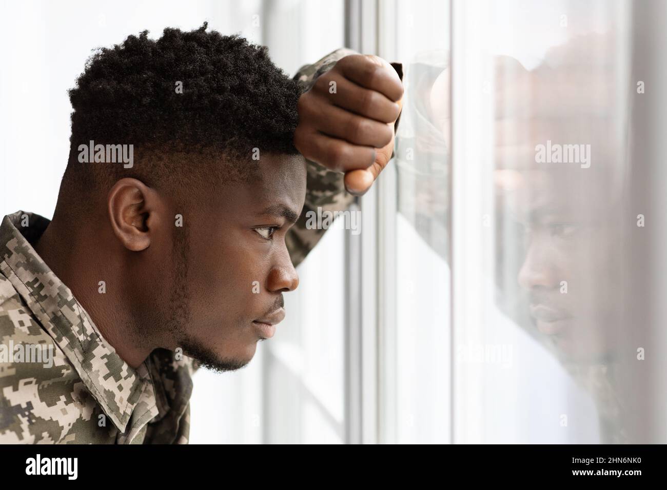 Pensive african american soldier looking through window at home Stock Photo